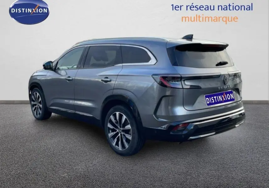 Vue 3/4 arrière droite d'un Renault Espace gris 2024 avec barres de toit et jantes aluminium.