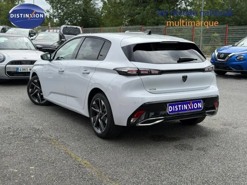 Peugeot 308 blanc Okénite vue 3/4 arrière droit, jantes alu et feux arrière LED distinctifs.
