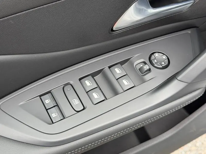 Vue rapprochée des commandes de lève-vitres et rétroviseurs sur la porte côté gauche intérieure d'une Peugeot 308 blanche.