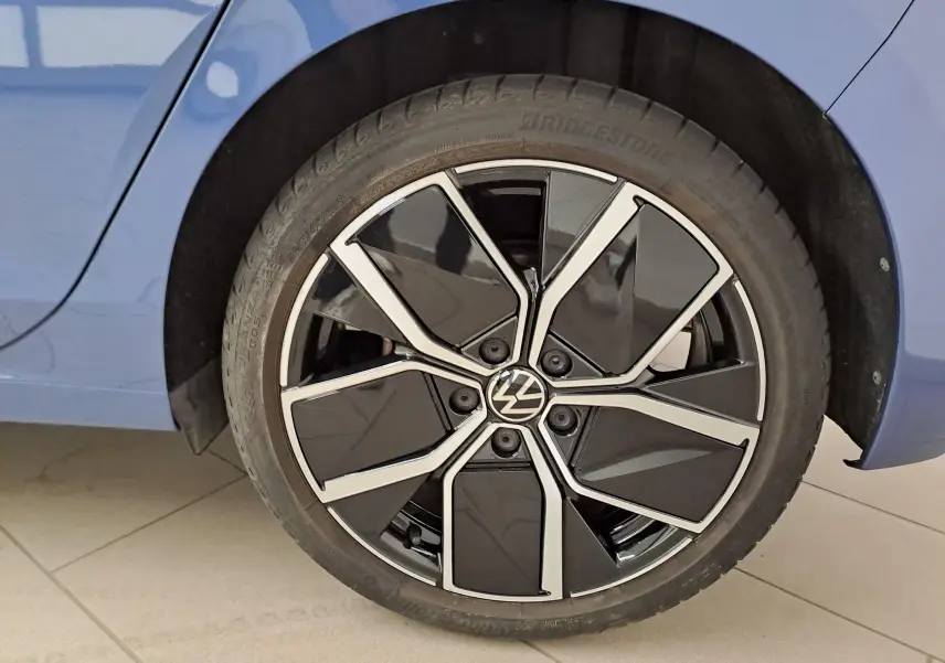 Gros plan sur la roue avant droite avec jante noire et argentée de la Volkswagen Golf Bleu Anémone 2024.