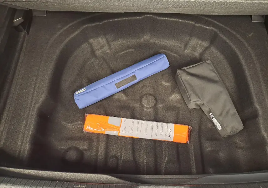 Coffre ouvert vu de dessus d'une Volkswagen Golf 2024, version Bleu Anémone, avec accessoires de sécurité posés.