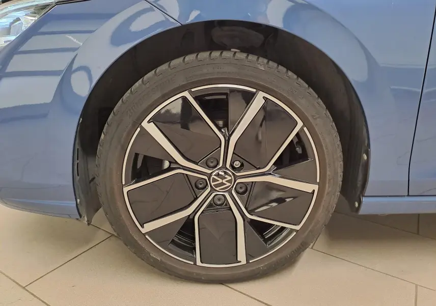 Gros plan sur la roue avant gauche de la Volkswagen Golf Bleu Anémone avec jante alliage noire et argentée.