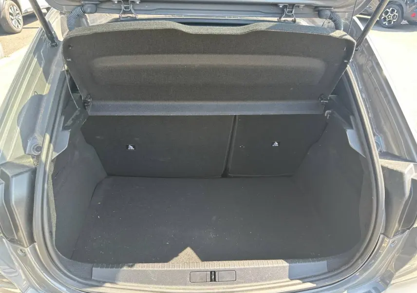 Coffre ouvert vu de l'arrière d'une Peugeot 208 1.2 100ch gris Selenium avec banquette arrière rabattable.