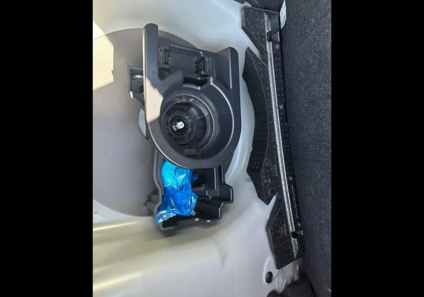 Détail du coffre de la Peugeot 208 2025 gris Selenium, montrant le rangement pour roue de secours et outils.