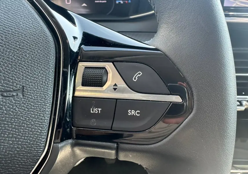 Gros plan sur les commandes gauche du volant noir de la Peugeot 208 Gris Selenium avec boutons audio et téléphone.