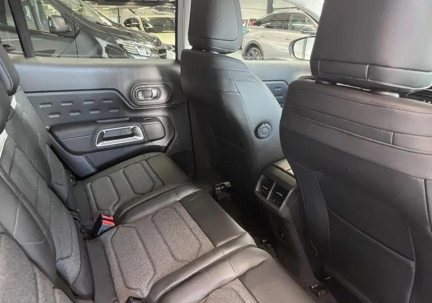 Vue intérieure arrière côté gauche du Citroën C5 Aircross 2025 avec sièges tissu et cuir gris et aérateurs centraux.