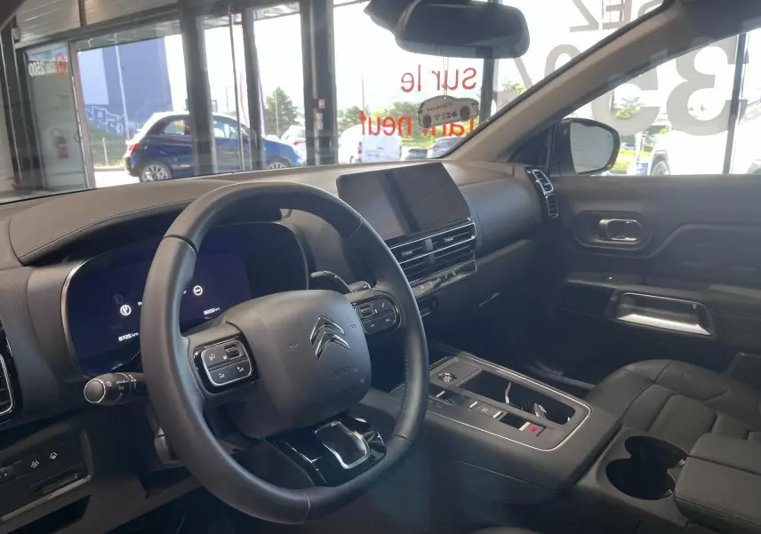 Intérieur du Citroën C5 Aircross 2025 en vue côté conducteur, volant cuir noir et écran tactile central.