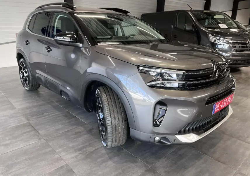 Citroën C5 Aircross gris platinium en 3/4 avant droit, avec jantes alliage bi-ton et barres de toit noires.