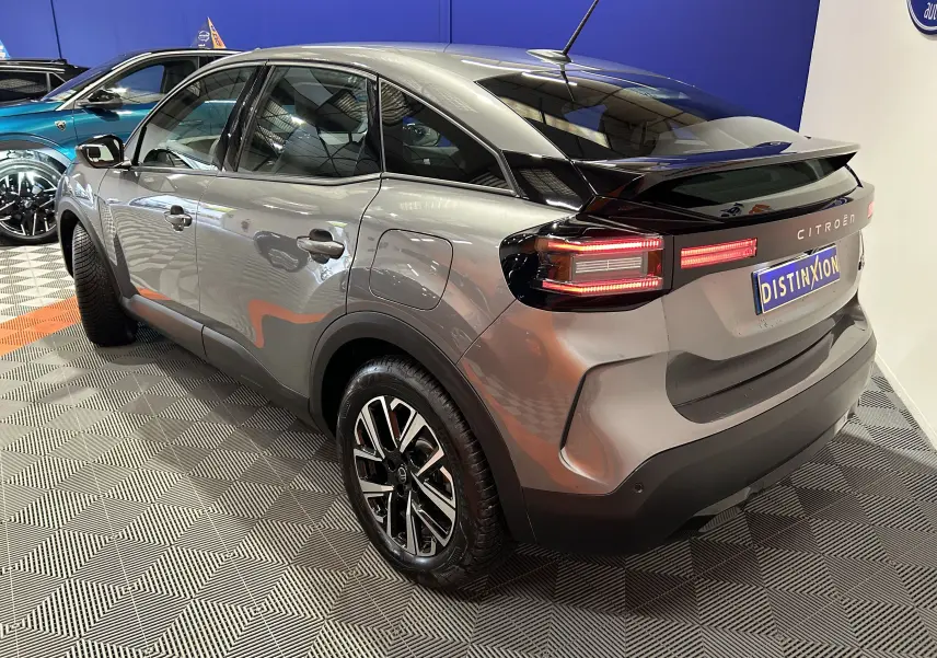 Vue 3/4 arrière droite d'une Citroën E-C4 électrique gris foncé avec feux arrière LED et jantes alliage noires.