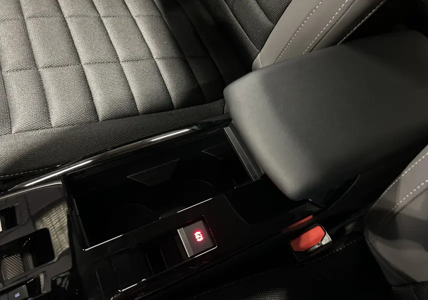 Gros plan sur la console centrale noire et accoudoir gris foncé du Citroën E-C4 électrique 2025, intérieur tissu.