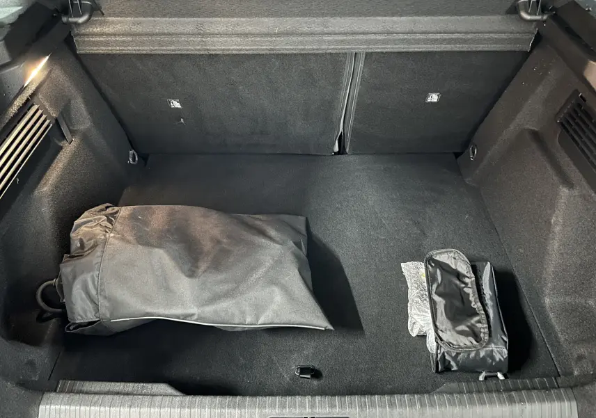 Vue plongeante sur le coffre spacieux et propre du Citroën E-C4 gris foncé avec accessoires rangés.