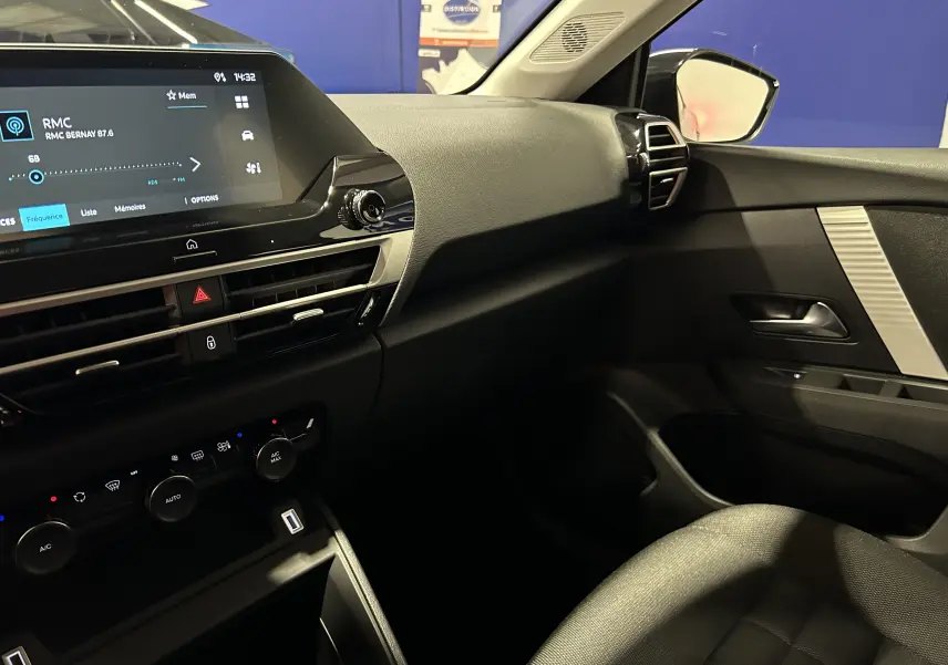 Vue intérieure côté passager du tableau de bord et de la porte noire du Citroën E-C4 2025 avec écran tactile allumé.