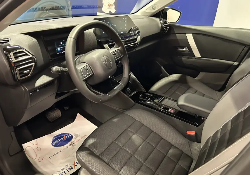 Vue intérieure côté conducteur du Citroën E-C4 gris foncé, avec tableau de bord numérique et volant multifonction.