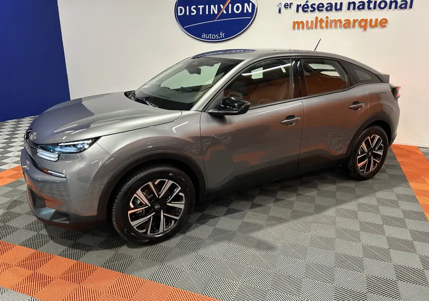 Vue 3/4 avant droit d'une Citroën E-C4 électrique gris foncé avec jantes noires et détails LED visibles.