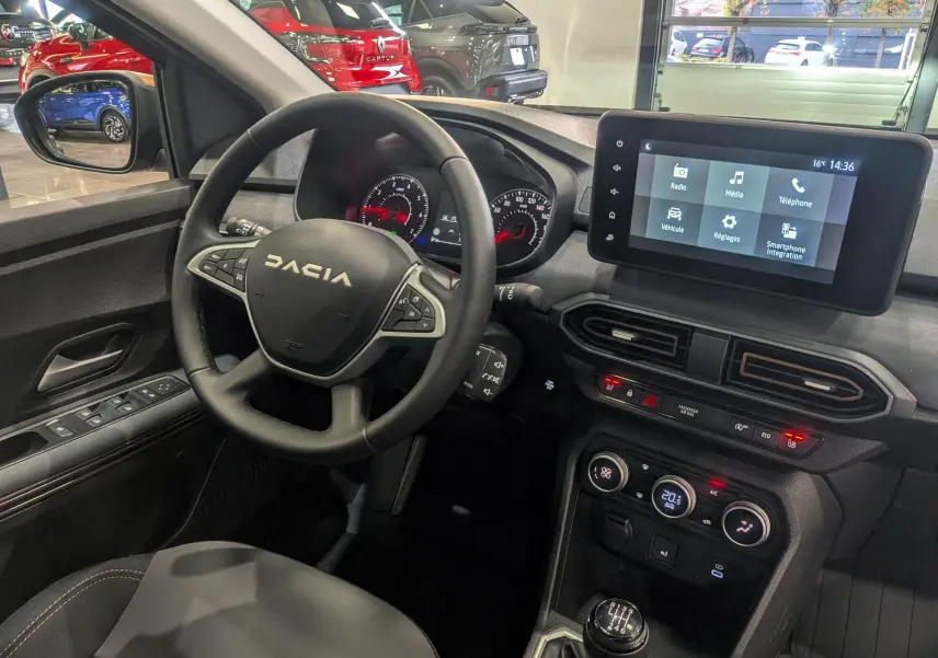 Vue intérieure du poste de conduite de la Dacia Sandero Stepway TCe 110 gris Schiste, avec volant multifonction et écran tactile central.