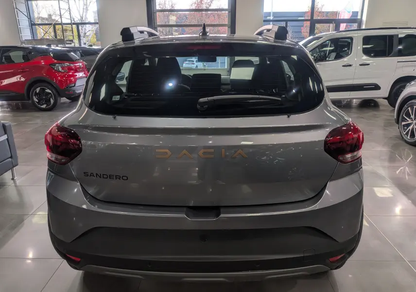 Vue arrière d'une Dacia Sandero Stepway gris schiste dans un showroom, avec logo et feux arrière visibles.