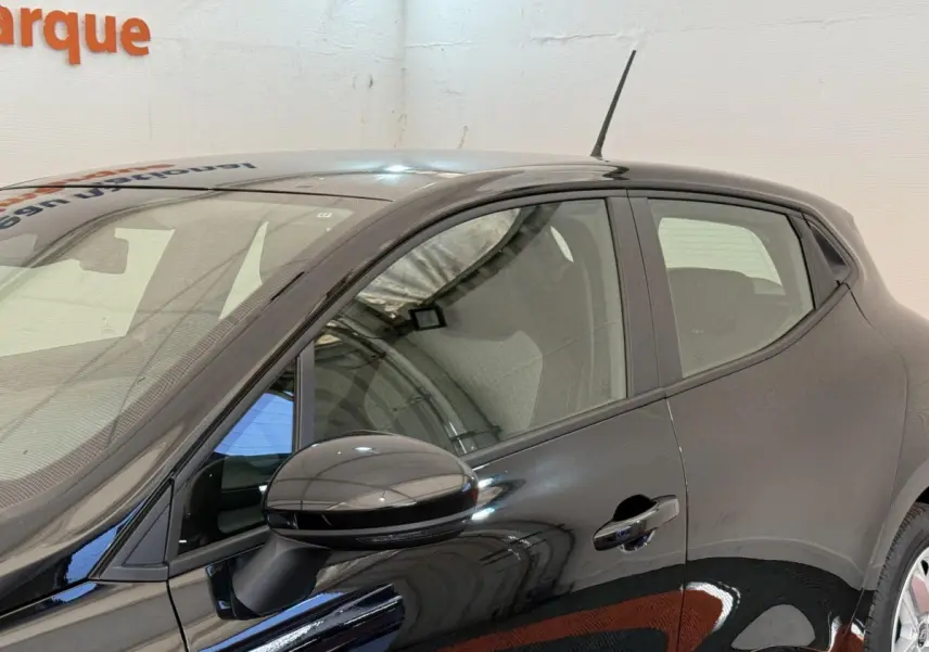 Vue latérale côté gauche d'une Renault Clio noire 2025 avec rétroviseur ton caisse et poignées de porte visibles.