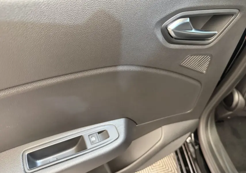 Détail de la porte avant gauche noire de la Renault Clio 2025 avec poignée argentée et commande de vitre électrique.