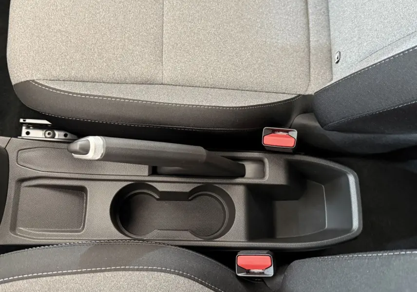 Vue rapprochée de la console centrale noire avec frein à main et sièges tissu gris de la Renault Clio 2025.