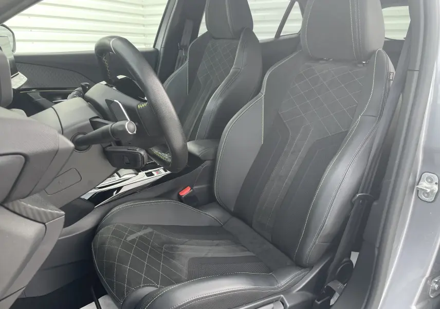 Vue intérieure côté conducteur du Peugeot 2008 gris Artense 2022, sièges sport en cuir et alcantara avec surpiqûres vertes.