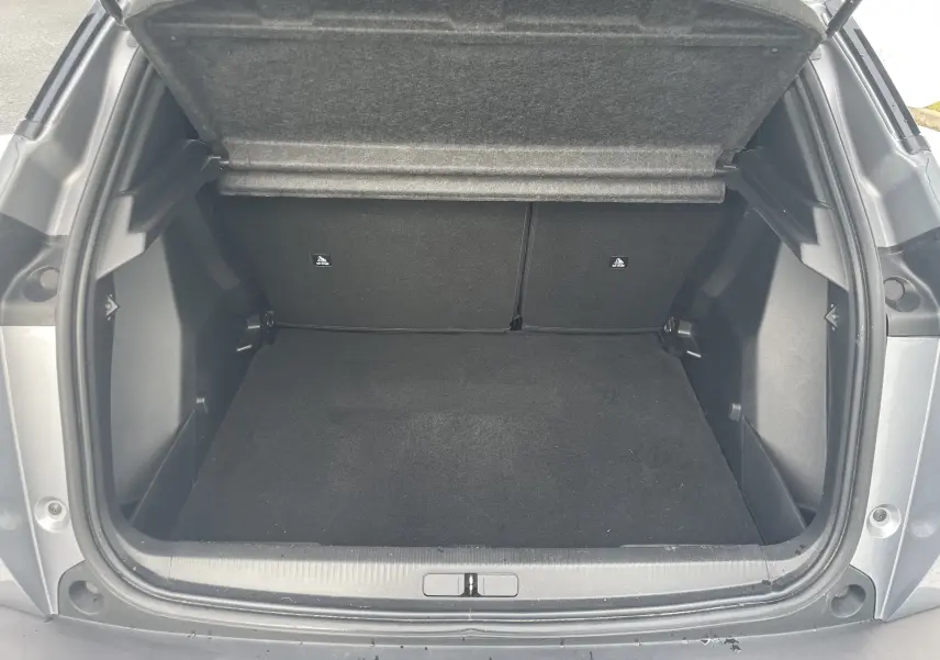 Coffre ouvert vu de l'arrière d'un Peugeot 2008 gris Artense, montrant un espace de chargement vide et propre.