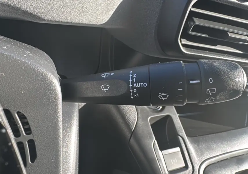 Gros plan sur la commande des essuie-glaces du Peugeot Rifter 2025, intérieur noir avec aérateurs visibles.