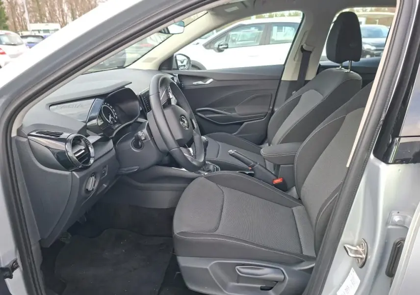 Vue intérieure côté conducteur de la Skoda Fabia Ambition 2023 gris argent, montrant sièges tissu et tableau de bord moderne.
