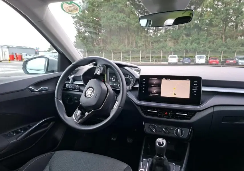 Vue intérieure côté conducteur de la Skoda Fabia Ambition 2023, avec tableau de bord noir et écran tactile central allumé.