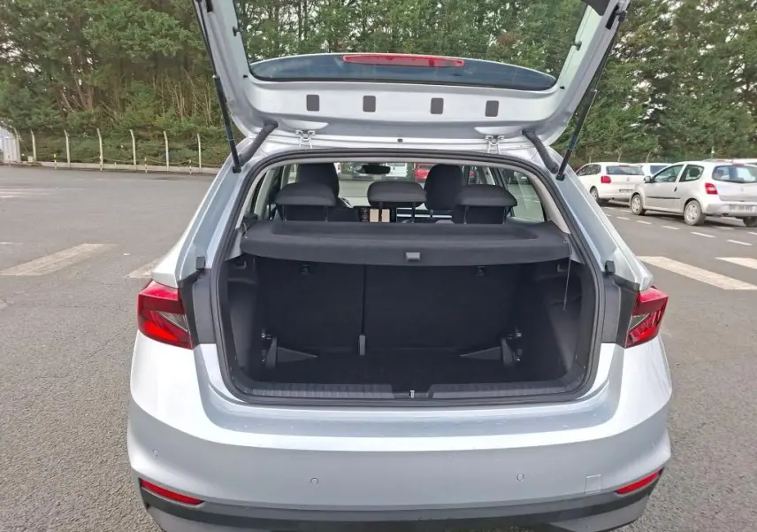 Vue arrière ouverte d'une Skoda Fabia Ambition 2023 gris argent, montrant le coffre spacieux et les feux arrière rouges.