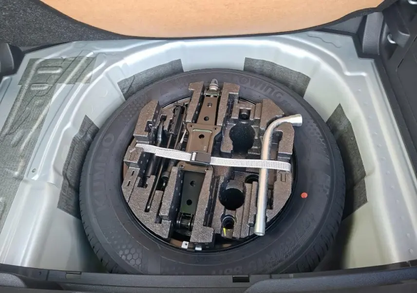 Vue plongeante sur la roue de secours et les outils de bord dans le coffre d'une Skoda Fabia gris argent 2023.