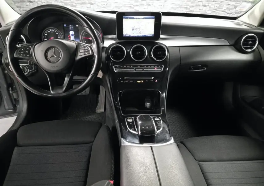 Vue intérieure avant de la Mercedes Classe C 200 d 2018, tableau de bord noir avec écran central et volant multifonctions.