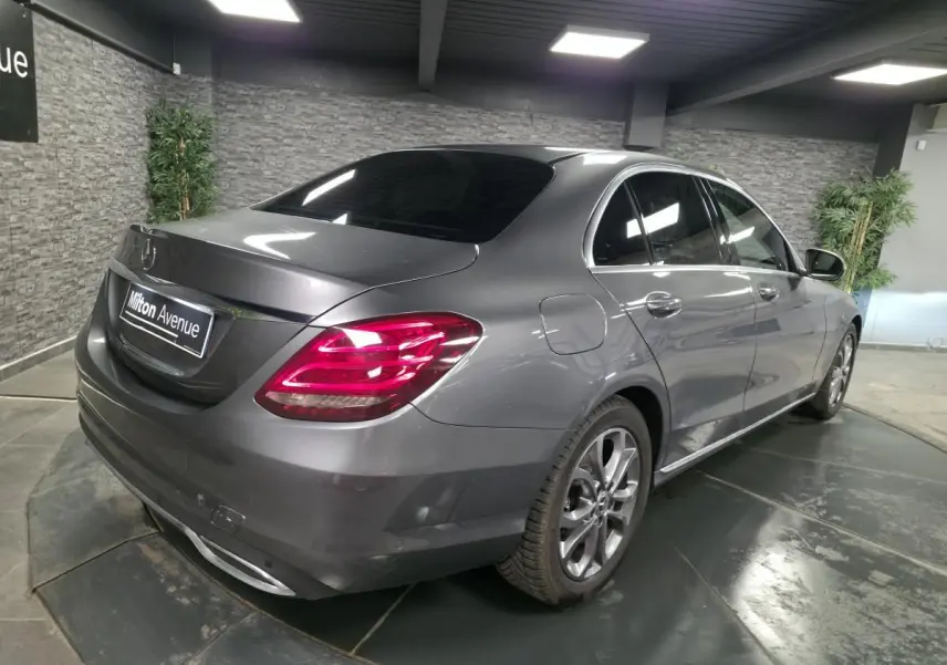 Mercedes Classe C 200 d gris métallisé vue 3/4 arrière droit, avec jantes alliage 17 pouces et feux arrière LED allumés.
