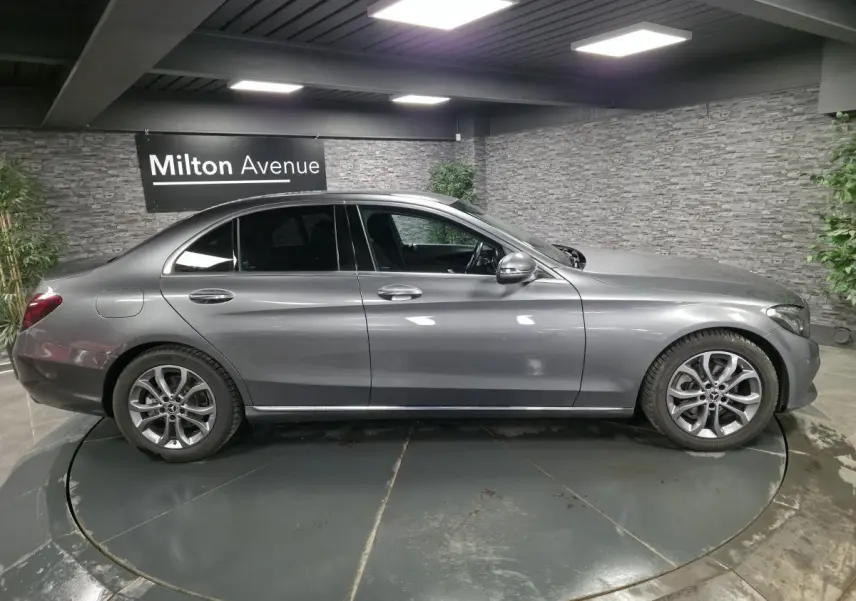 Profil côté droit d'une Mercedes Classe C gris métallisé avec jantes alliage 17 pouces dans un showroom.
