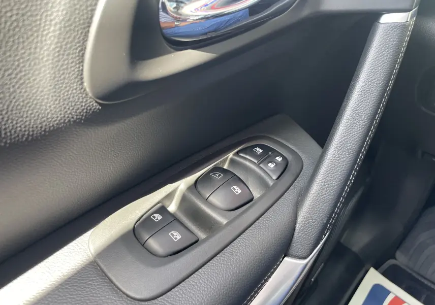 Gros plan sur les commandes des vitres électriques côté gauche de la porte intérieure d’un Renault Kadjar rouge flamme.