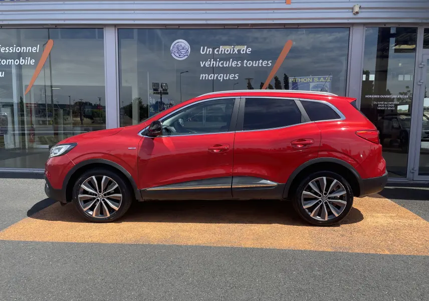 Vue de profil côté gauche d'un Renault Kadjar rouge flamme 2018 avec jantes alliage bicolores et vitres teintées.