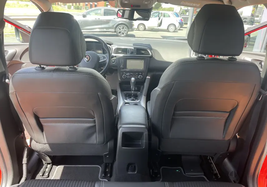 Vue intérieure arrière du Renault Kadjar rouge flamme 2018, montrant les sièges avant en cuir noir et la console centrale.