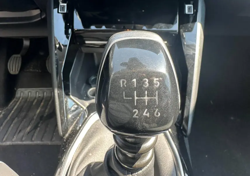 Gros plan sur le levier de vitesses manuel noir de la Peugeot 208 1.2 100ch Allure, entouré de la console centrale noire.