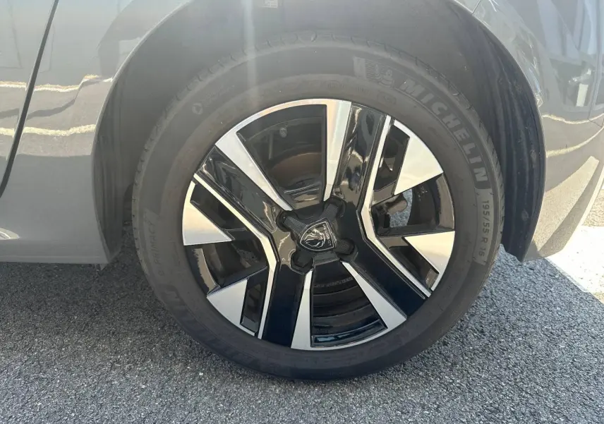 Gros plan sur la jante alu noire et argentée de la roue avant droite d’une Peugeot 208 gris Selenium.