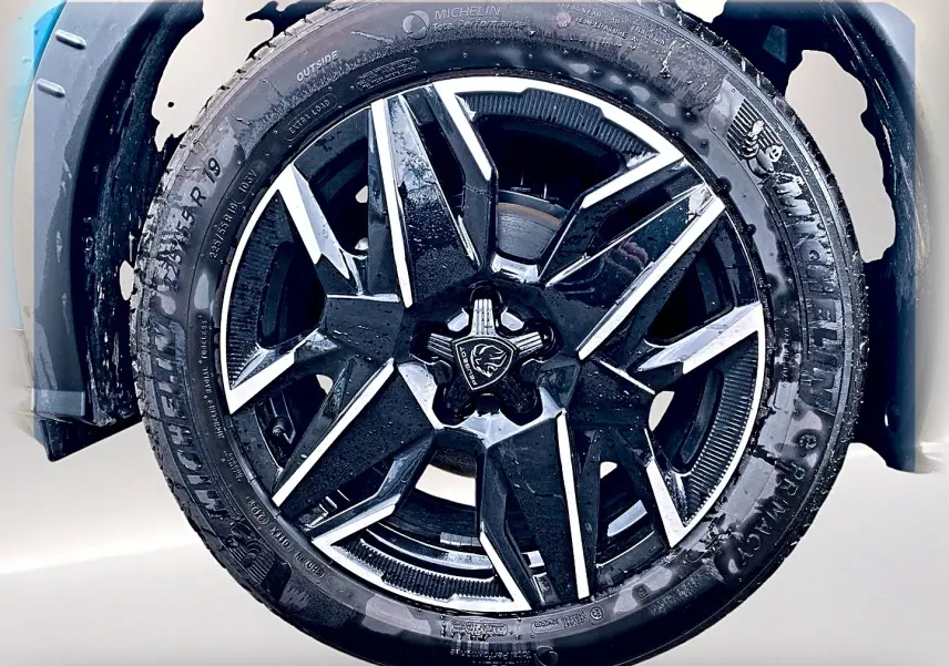 Gros plan sur la jante alu noire et argentée du côté avant gauche du Peugeot 3008 bleu 2025.