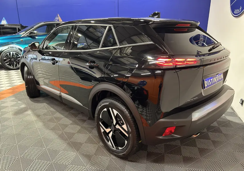 Peugeot 2008 hybride noire vue 3/4 arrière droit, avec feux LED allumés et jantes noires distinctives.