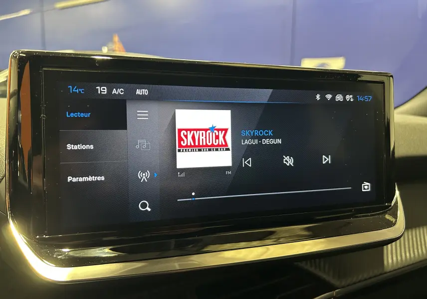Écran tactile central de la Peugeot 2008 II Hybrid noir affichant la radio Skyrock en mode lecteur à 14h57.