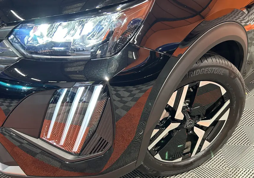 Gros plan sur l'avant droit noir du Peugeot 2008 II Hybrid avec ses phares LED et jante alliage distinctive.