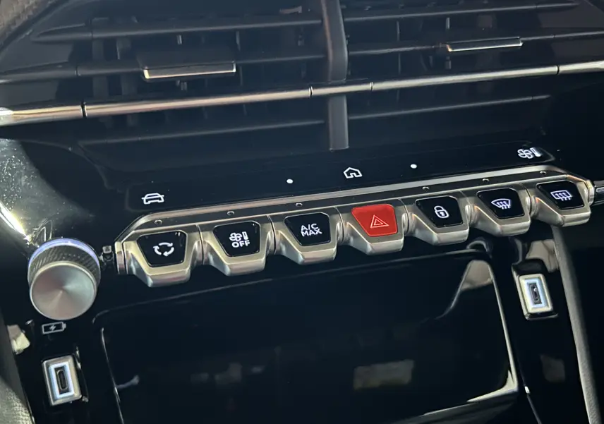 Gros plan sur la console centrale du Peugeot 2008 II Hybrid noir, avec boutons de commande et écran tactile.