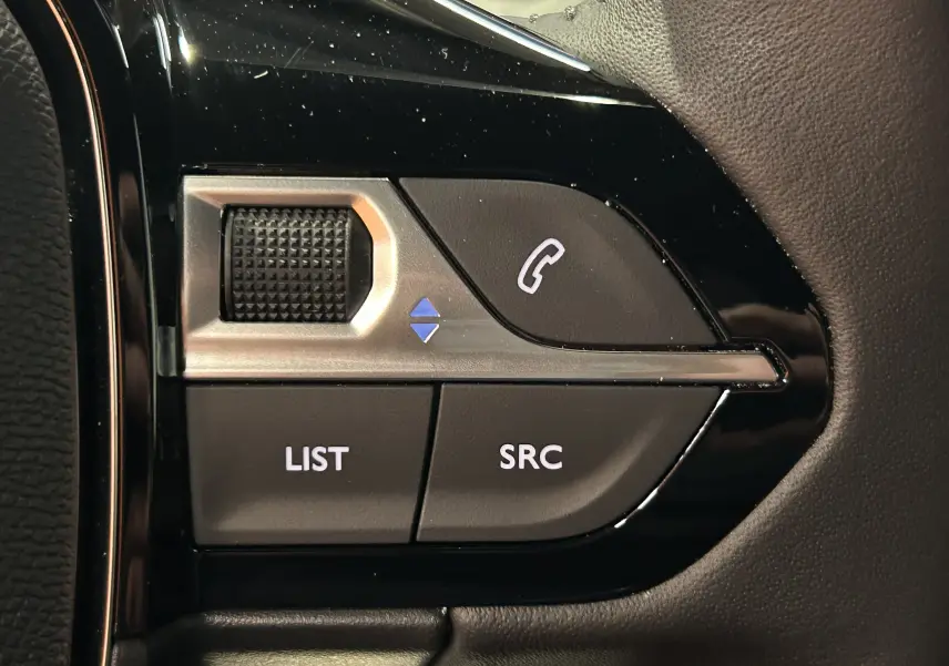 Gros plan sur les commandes multifonctions noires et argentées au volant du Peugeot 2008 II Hybrid 110 Allure.