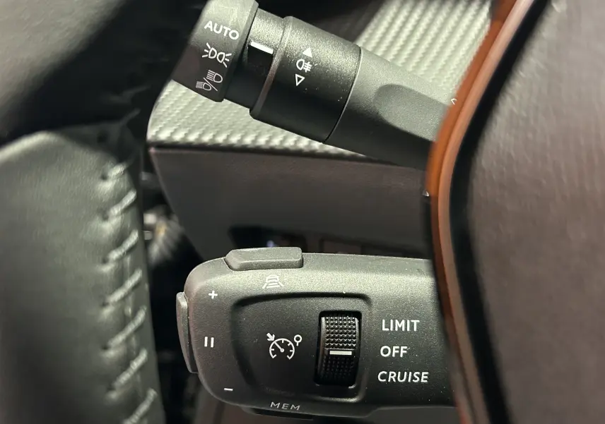 Gros plan sur la commande du régulateur de vitesse au volant d’un Peugeot 2008 noir, intérieur sombre.