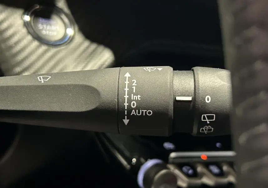 Gros plan sur la commande d’essuie-glace du Peugeot 2008 noir, avec bouton start visible en arrière-plan.