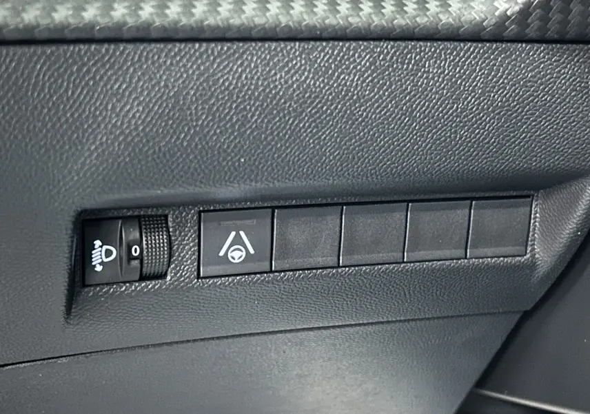 Gros plan sur les commandes de réglage des phares et d’assistance au maintien de voie dans l’habitacle d’une Peugeot 2008 noire.