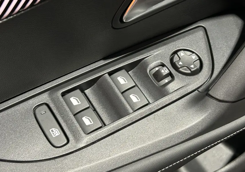 Gros plan sur les commandes de lève-vitres et réglage des rétroviseurs côté conducteur, intérieur noir du Peugeot 2008.