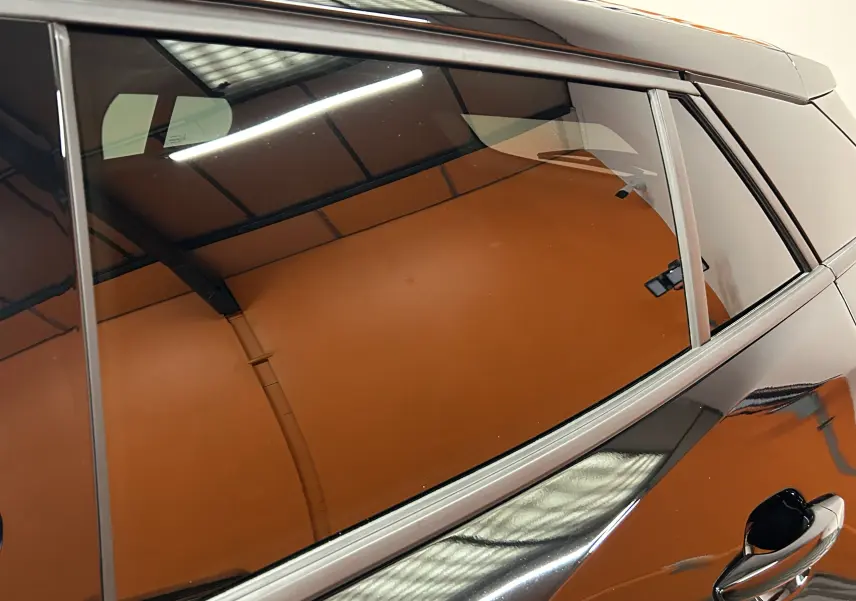Vue rapprochée du côté gauche arrière d’un Peugeot 2008 noir brillant avec reflet d’éclairage intérieur.