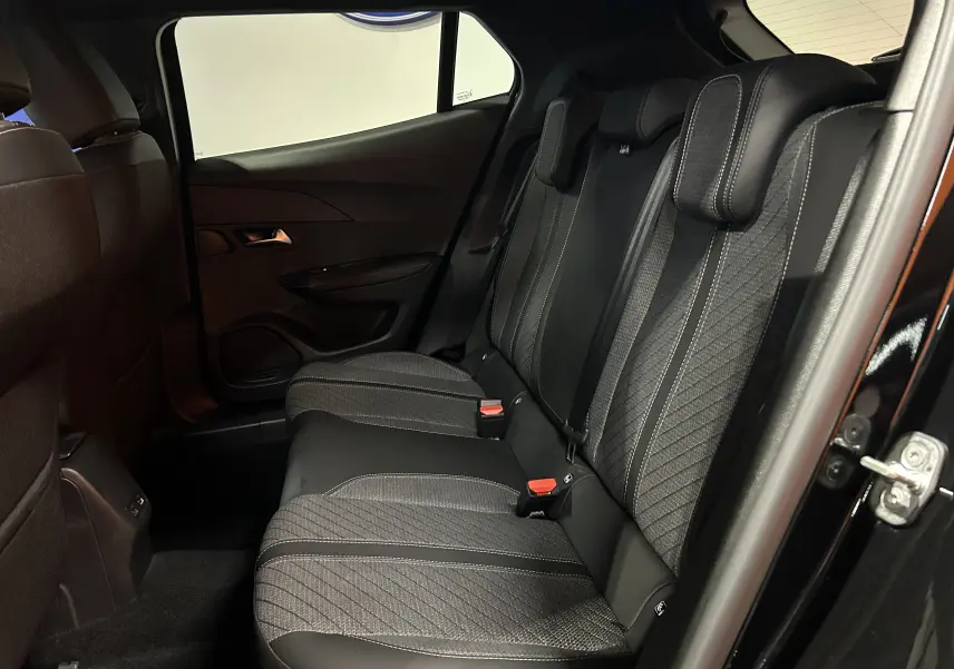Vue intérieure côté droit des sièges arrière noirs du Peugeot 2008 II Hybrid 110 avec détails de couture contrastée.